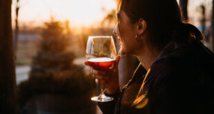 Young,Woman,Holding,A,Glass,Of,Red,Wine,,Outdoors,,At